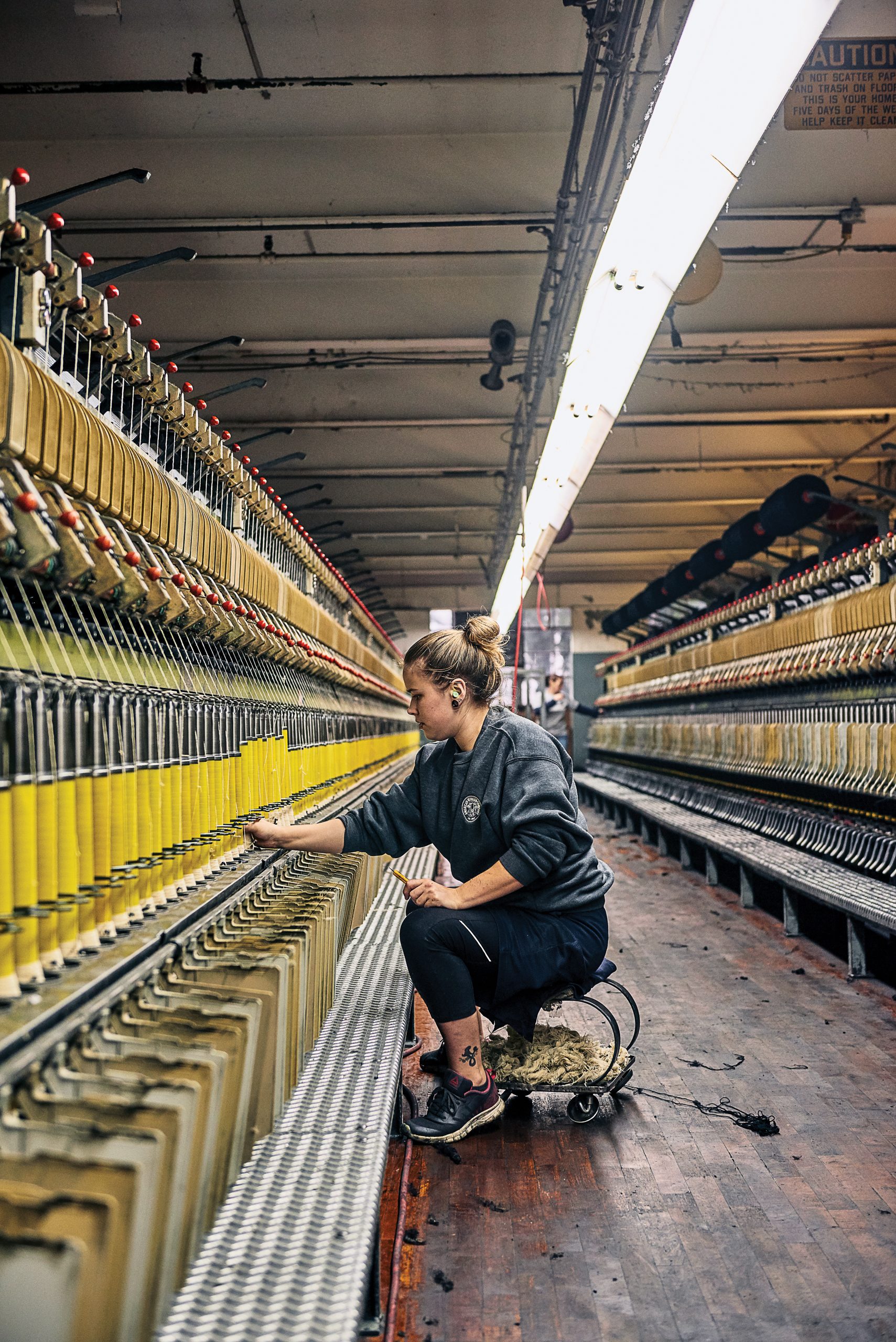 An American Woolen staffer tends to a woolen spinning frame